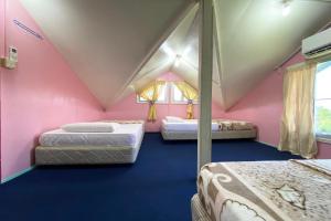 Habitación de color rosa con 3 camas en OYO HOME 90285 Pogimpaan Homestay en Ranau