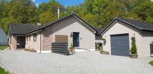 a brick house with a garage and a driveway at Ridgewood Apartment in Drumnadrochit