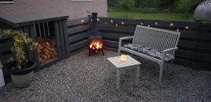 a fire pit next to a bench and a fire grill at Ridgewood Apartment in Drumnadrochit