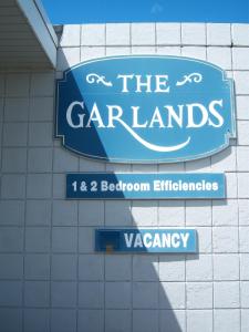 una señal azul para los jardines y una señal para los carllantes en The Garlands Motel, en Dennis Port