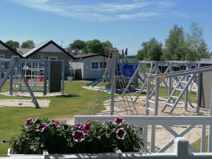 um parque infantil com um baloiço e flores em Holiday-Camp em Rusinowo