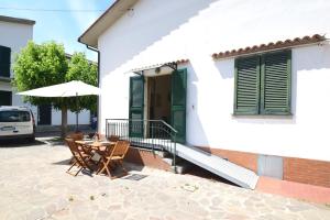 a patio with a table and an umbrella in front of a house at PRIMAVERA TRILO - Zona mare con spazio esterno, clima e posto auto in Marina di Campo