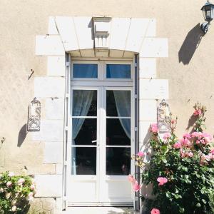 a white door with a window and pink flowers at La Fedrie in La Croix-en-Touraine