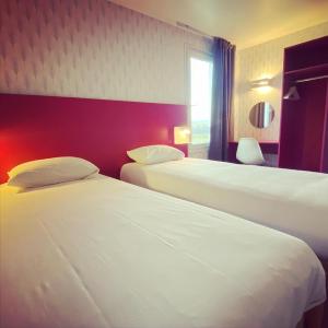 een hotelkamer met 2 bedden en een raam bij Fasthôtel Clermont-Ferrand Gerzat in Gerzat