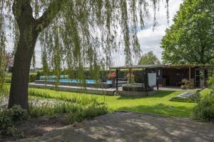 un jardin avec une maison et un arbre dans l'établissement Bed & Breakfast De Heughte, à Oosterwolde