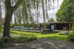 un jardín con una casa y un árbol en Bed & Breakfast De Heughte, en Oosterwolde