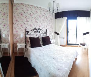 1 dormitorio con cama blanca y papel pintado de flores rosas en La guardia ll, en A Guarda