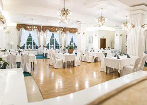 uma sala de jantar com mesas e cadeiras brancas e lustres em Hotel Villa Riviera em Rzeszów