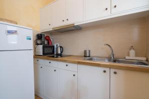 eine Küche mit weißen Schränken, einer Spüle und einem Kühlschrank in der Unterkunft Koukaki Groove Aptm - Acropolis walking distance in Athen