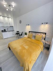 a large yellow bed in a room with a kitchen at Apartment Studio New York 45 in Irpin'