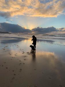 a man standing on the beach with a dog at Lochindaal Hotel in Port Charlotte