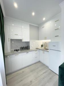 cocina blanca con armarios blancos y suelo de madera en Luxury Emerald Apartments, en Irpín