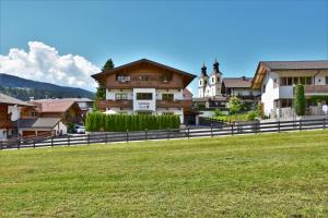 eine Gruppe von Häusern auf einem Feld mit einem Zaun in der Unterkunft Landhaus Tirol in Hopfgarten im Brixental