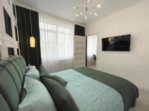 1 dormitorio con 1 cama grande y TV en Luxury Emerald Apartments, en Irpín
