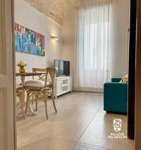 een woonkamer met een tafel en een televisie bij Palazzo Palasciano in Monopoli