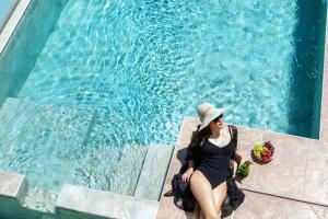 Eine Frau mit Hut neben einem Pool in der Unterkunft Sunny Villas Resort & Spa in Chaniotis