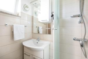 een witte badkamer met een wastafel en een douche bij Apartments Soul in Krk