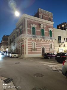 a pink and white building with cars parked in a parking lot at Palazzo Palasciano in Monopoli