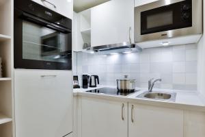 a white kitchen with a sink and a microwave at Mimosa House in Westerland +27 photos