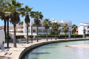 una piscina con palmeras frente a un edificio en Apartamentos venecia a unos pasos de la playa, en Puerto de Alcudia