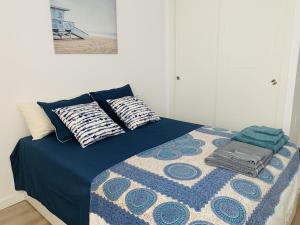 a bed with a blue comforter and pillows on it at ESTUPENDO APARTAMENTO ENTERO in Marbella +28 photos