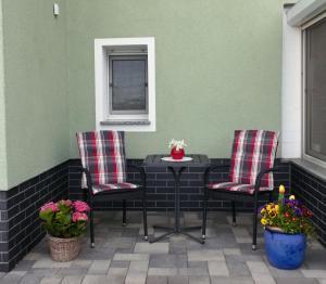 2 Stühle und ein Tisch auf einer Terrasse mit Blumen in der Unterkunft Ferienwohnung Schwarzkollm in Hoyerswerda