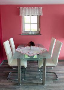 einen Esstisch mit weißen Stühlen und einer rosa Wand in der Unterkunft Ferienwohnung Schwarzkollm in Hoyerswerda