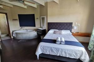 a bedroom with a bed and a bathtub and a bed with slippers at Luxury Villa Nelspruit in Nelspruit