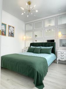 um quarto branco com uma cama verde e um lustre em Luxury Emerald Apartments em Irpin
