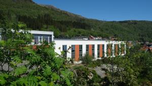 ein weißes Gebäude mit orangefarbenen Fenstern und einem Berg in der Unterkunft Bergen Hostel Montana in Bergen