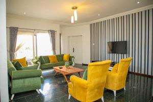 a living room with yellow chairs and a tv at St Georges Height in Accra