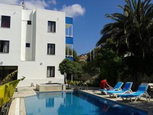 a man sitting next to a swimming pool next to a building at Parla Apart Hotel in Çeşme