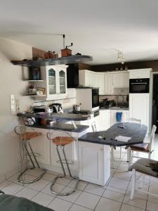 eine Küche mit weißen Schränken sowie einem Tisch und Stühlen in der Unterkunft Chambre chez l'habitant in Châteaubriant
