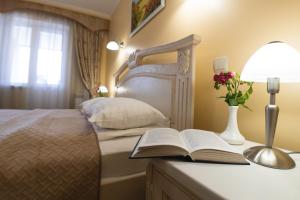 Dormitorio con cama con libro y lámpara en Hotel Ternopil en Ternopilʼ