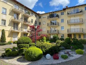 ソポトにあるSanhaus Apartments - Apartament Patio Mare z balkonemの茂みの建物前庭