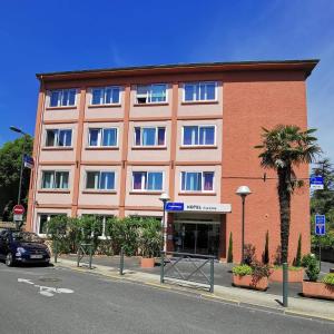 a large red building with blue windows on a street at The Originals City, Hôtel Rive Droite, Albi "Quartier Madeleine" in Albi