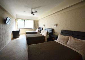Habitación de hotel con 2 camas y ventana en Hotel Diana del Bosque by DOT Urban en Morelia