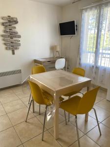 a dining room with a table and yellow chairs at Résidence Fort de l'Eve - T2 à 380m plage M Hulot et commerces - St Marc sur Mer idéal famille proche La Baule P0rnichet avec parking privé in Saint-Nazaire