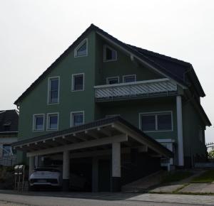 ein grünes Haus mit einem davor geparkt in der Unterkunft Ferienwohnung Schwarzkollm in Hoyerswerda