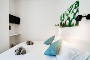 une chambre avec un lit blanc avec des oreillers bleus dans l'établissement White Loft Como Central - The House Of Travelers, à Côme