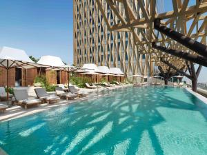 ein großer Pool mit Stühlen und ein Gebäude in der Unterkunft Four Seasons Hotel Kuwait at Burj Alshaya in Kuwait