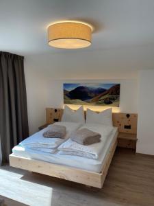 1 dormitorio con 1 cama con sábanas y almohadas blancas en Dorfblick Appartements & Rooms, en Senales