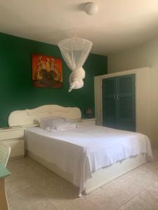 um quarto com uma cama branca e uma parede verde em Carthago em Mbour