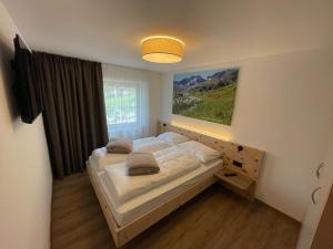 a bedroom with a bed with a large window at Dorfblick Appartements & Rooms in Senales