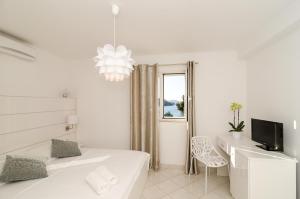 a white bedroom with a bed and a desk and a television at Villa Babilon in Zaton