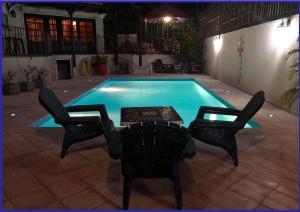 a swimming pool with two chairs and a table in front of it at Villa Labrousse (Atypical) in Le Gosier