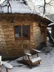 une cabane en rondins avec une chaise dans la neige dans l'établissement Parthénope - Les Cabanes du Chêne Rouvre, à Saint-Dié-des-Vosges