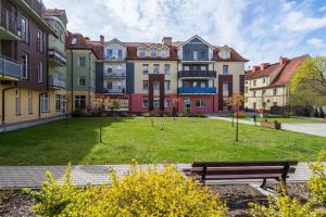 um parque com um banco em frente a um grande edifício em Golden Apartament - Żeglarska em Giżycko