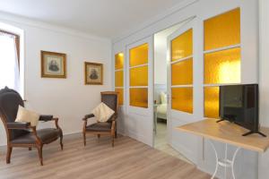 uma sala de estar com duas cadeiras e uma televisão em La Maison Oberlin em Horbourg