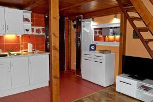 eine Küche mit weißen Schränken und einem Flachbild-TV in der Unterkunft Halkoz Apartment in Debrecen